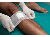 A bandage being applied to a wound on a man's leg.